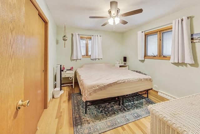 bedroom with ceiling fan, light hardwood / wood-style flooring, a closet, and a baseboard radiator