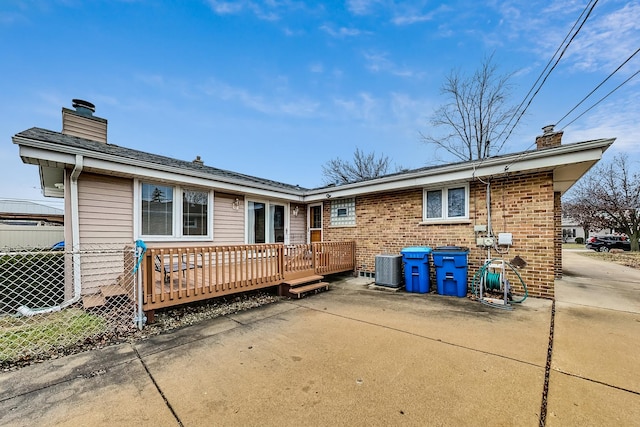 rear view of house with a wooden deck and a patio