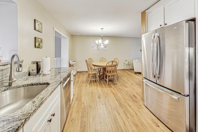 kitchen featuring sink, stainless steel appliances, light stone countertops, white cabinets, and light wood-type flooring