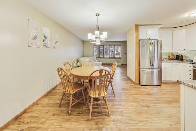 dining space with an inviting chandelier and light hardwood / wood-style flooring