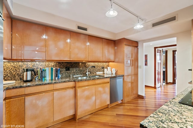 kitchen with sink, backsplash, dark stone counters, stainless steel dishwasher, and light hardwood / wood-style flooring