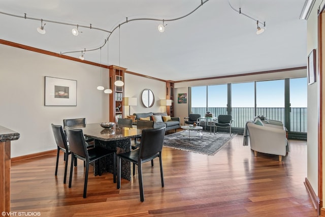 dining area with hardwood / wood-style flooring, ornamental molding, and a water view