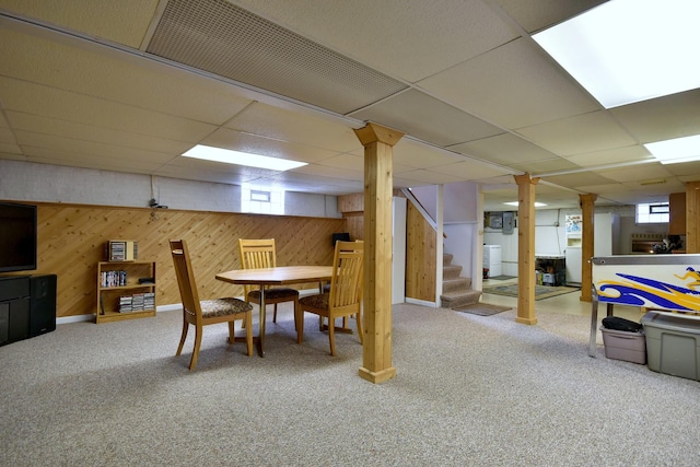 basement with carpet floors, stairway, wood walls, and a paneled ceiling