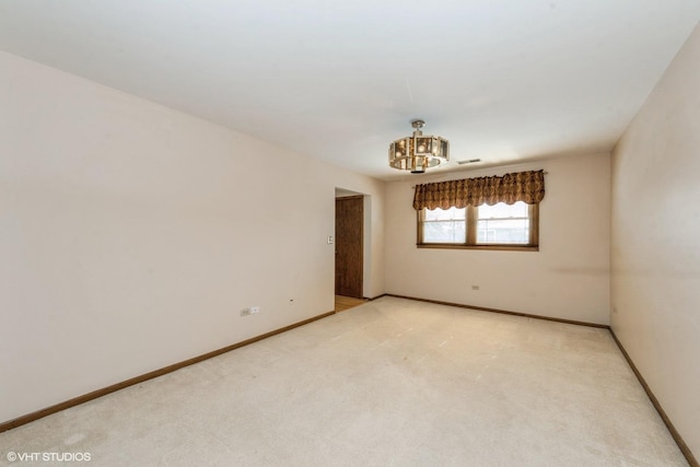 carpeted empty room featuring a notable chandelier