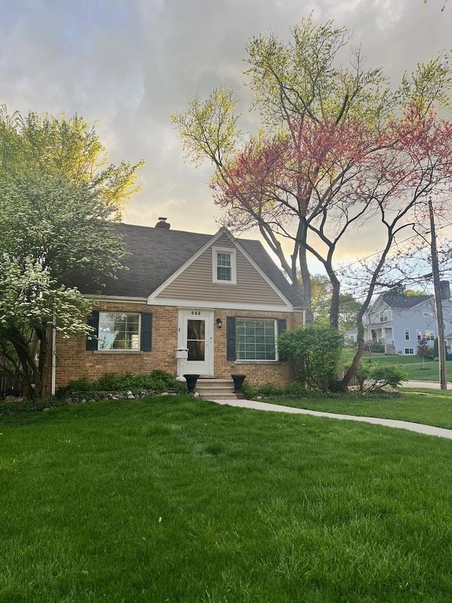 view of front of house featuring a yard and brick siding