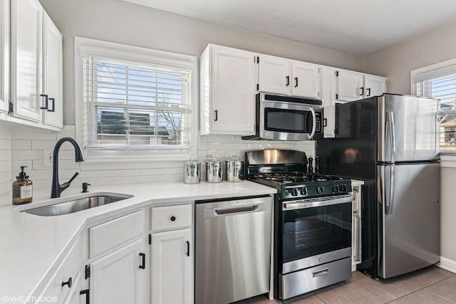 kitchen featuring appliances with stainless steel finishes, backsplash, a sink, and white cabinets