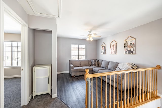 living area featuring ceiling fan, dark carpet, and baseboards