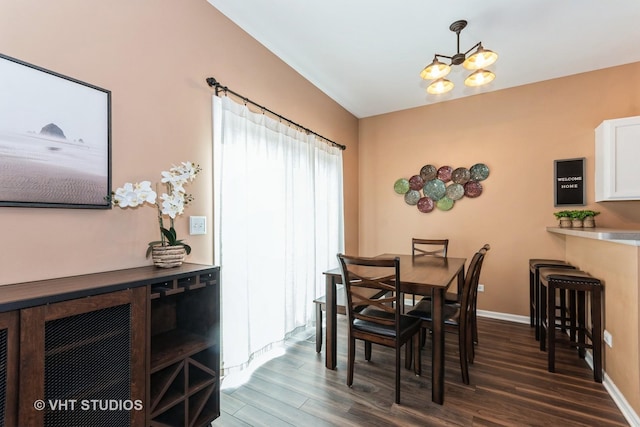 dining room featuring dark wood-style floors, baseboards, and an inviting chandelier