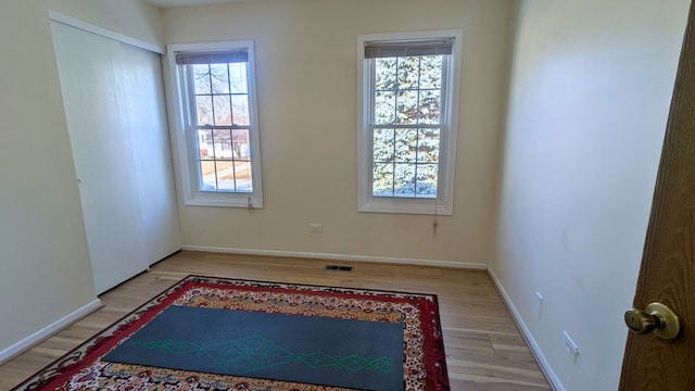 empty room featuring light wood finished floors, visible vents, and baseboards