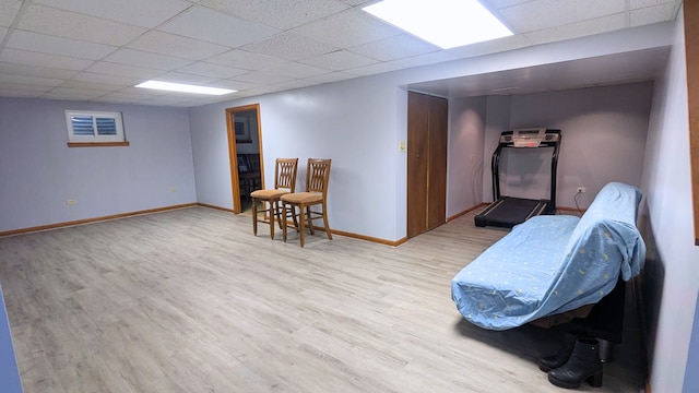 interior space featuring baseboards, a drop ceiling, and light wood-style floors