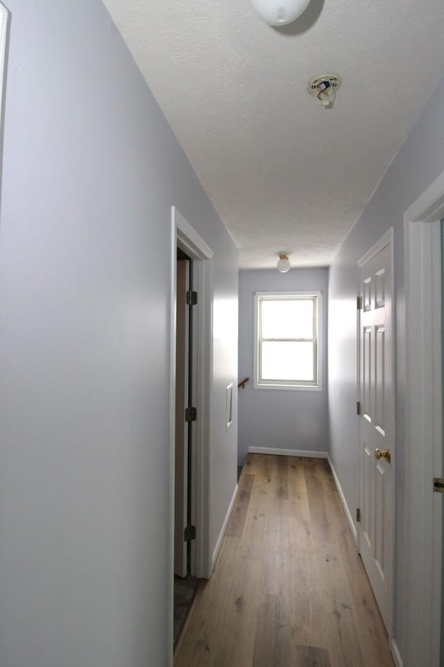 hall with light hardwood / wood-style floors and a textured ceiling