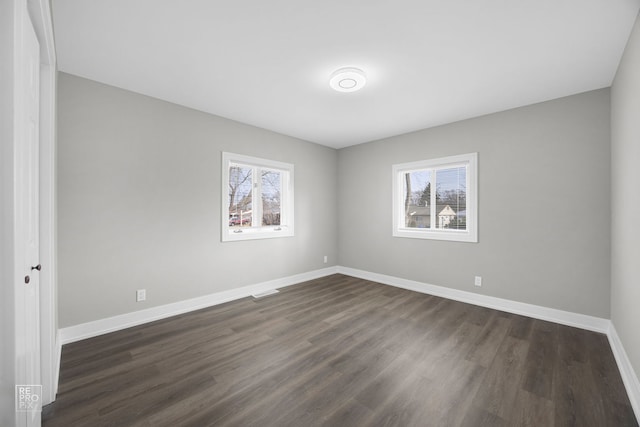 spare room featuring a healthy amount of sunlight and dark wood-type flooring