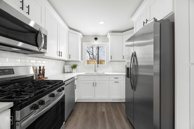 kitchen featuring sink, dark wood-type flooring, appliances with stainless steel finishes, white cabinets, and decorative backsplash