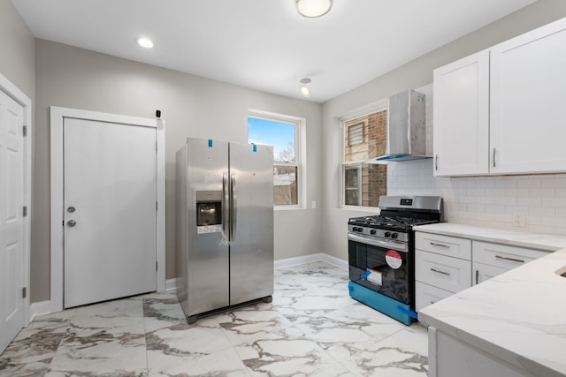 kitchen with light stone counters, white cabinets, stainless steel appliances, and wall chimney exhaust hood