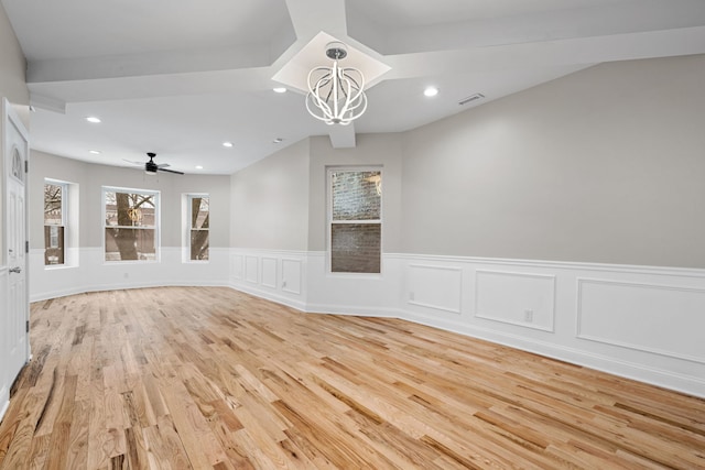 spare room featuring ceiling fan with notable chandelier and light hardwood / wood-style floors