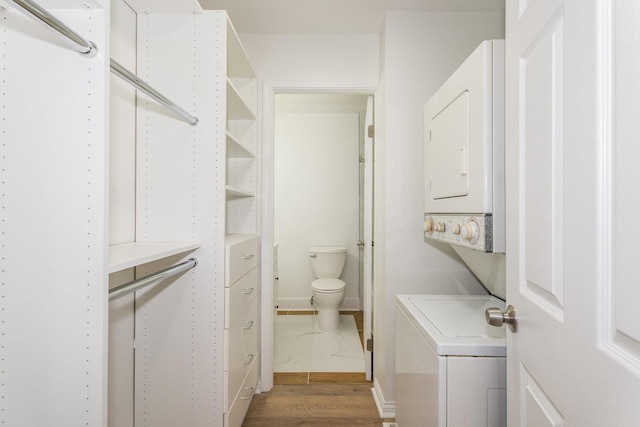 walk in closet with stacked washer / drying machine and wood finished floors