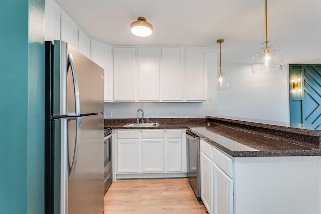 kitchen with light wood-style flooring, a peninsula, white cabinets, stainless steel appliances, and a sink