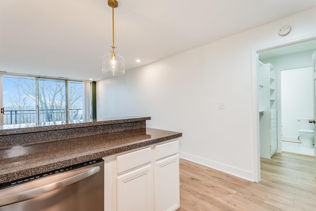 kitchen featuring dark countertops, white cabinets, light wood finished floors, dishwasher, and hanging light fixtures