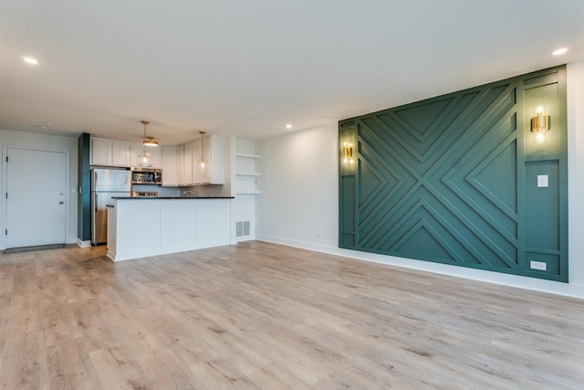 unfurnished living room with visible vents, recessed lighting, light wood-type flooring, and baseboards