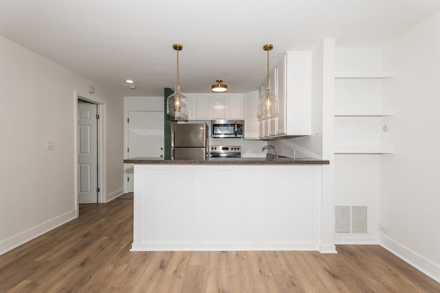 kitchen featuring visible vents, light wood-style flooring, appliances with stainless steel finishes, a peninsula, and white cabinets