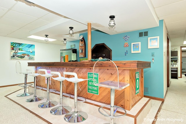 bar with baseboards, visible vents, and a dry bar