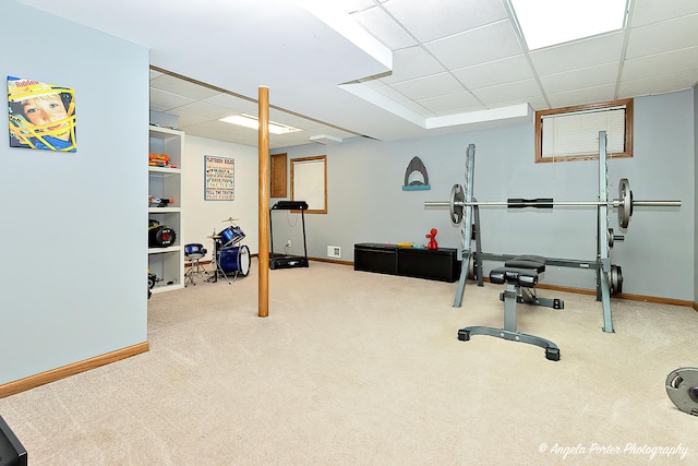 workout area featuring carpet floors, a paneled ceiling, and baseboards