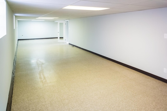 finished below grade area featuring a drop ceiling, tile patterned floors, and baseboards