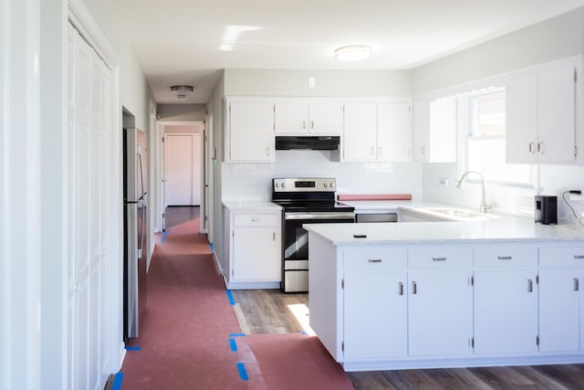 kitchen with under cabinet range hood, stainless steel appliances, a peninsula, white cabinets, and light countertops