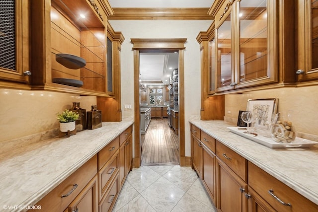 bar with light tile patterned floors, ornamental molding, and light stone countertops