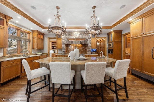 kitchen featuring decorative light fixtures, a tray ceiling, sink, and a spacious island