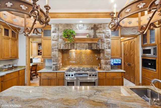 kitchen with sink, built in desk, light stone countertops, and appliances with stainless steel finishes