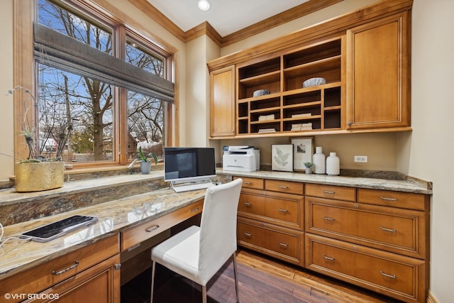 office with hardwood / wood-style floors, crown molding, built in desk, and a wealth of natural light