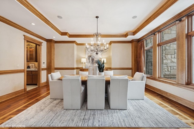 dining area with crown molding, a tray ceiling, a chandelier, and hardwood / wood-style floors