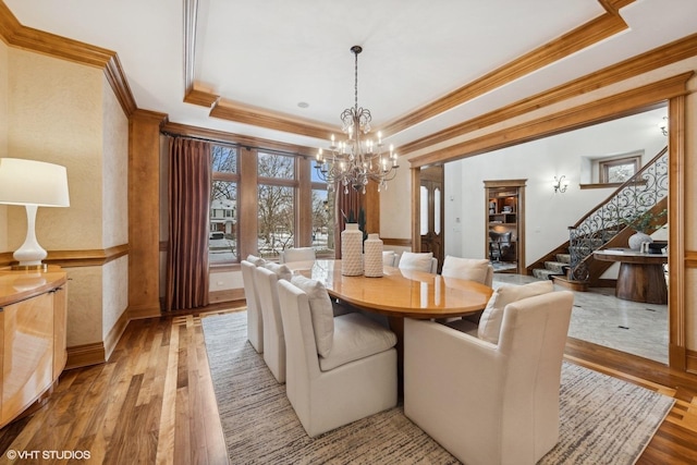 dining area with ornamental molding, a raised ceiling, and light hardwood / wood-style floors