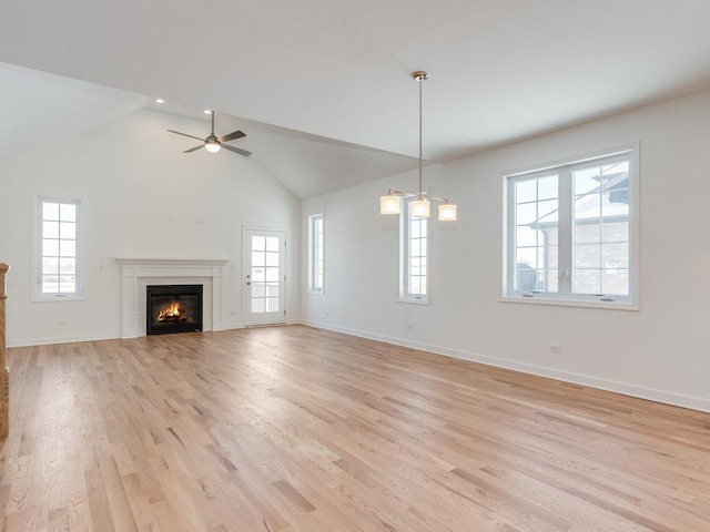 unfurnished living room with light wood-style floors, a wealth of natural light, a glass covered fireplace, and baseboards