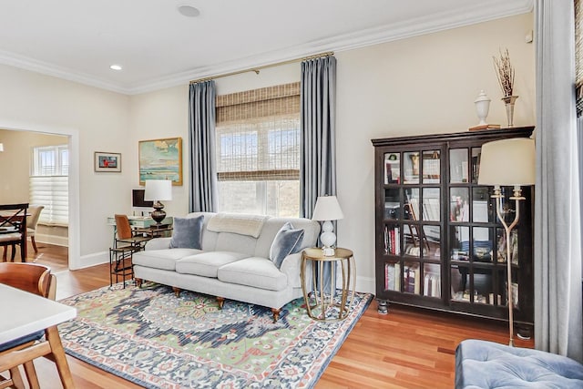 living room with a wealth of natural light, crown molding, baseboards, and wood finished floors