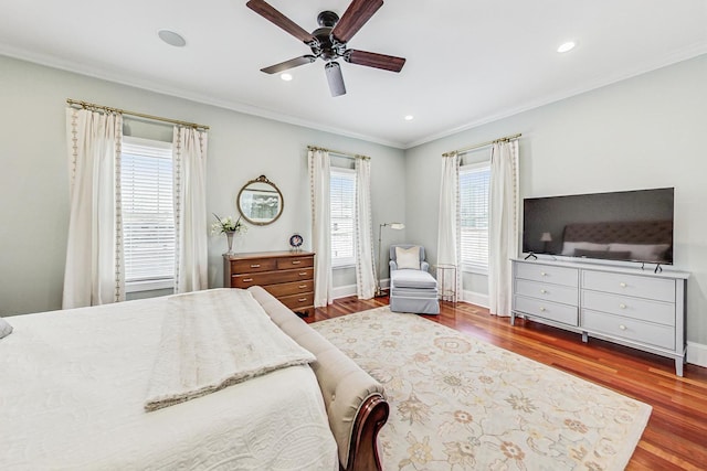 bedroom featuring baseboards, multiple windows, wood finished floors, and crown molding