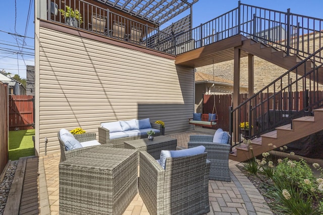 view of patio / terrace featuring stairs, fence, and an outdoor living space