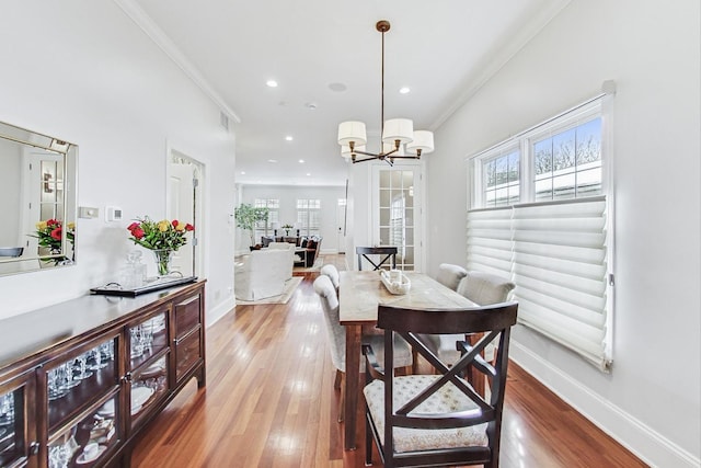 dining room featuring baseboards, crown molding, hardwood / wood-style floors, and an inviting chandelier