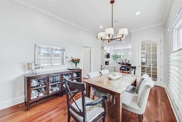 dining space featuring a healthy amount of sunlight, crown molding, an inviting chandelier, and wood finished floors