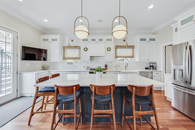 kitchen with stainless steel appliances, a center island, crown molding, and a sink