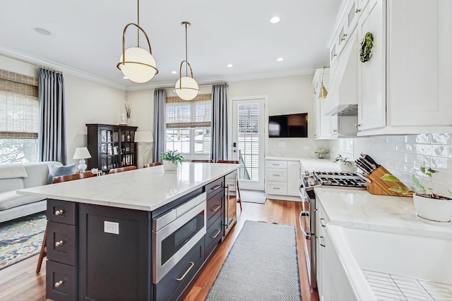 kitchen with stainless steel appliances, white cabinetry, ornamental molding, and decorative backsplash