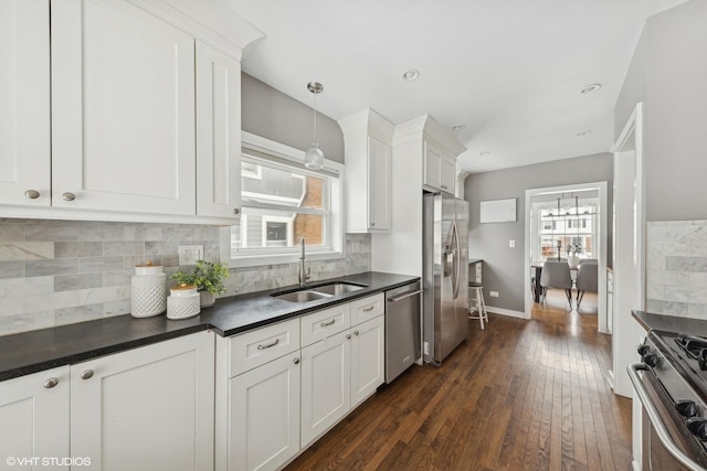 kitchen featuring sink, appliances with stainless steel finishes, backsplash, white cabinets, and decorative light fixtures