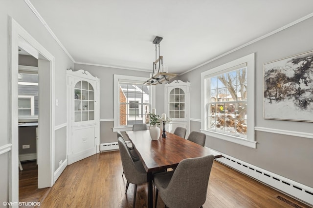 dining room with hardwood / wood-style flooring, ornamental molding, and a baseboard heating unit