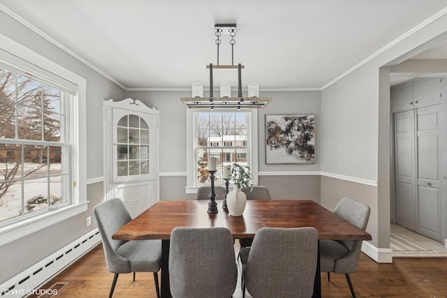 dining room featuring hardwood / wood-style flooring, ornamental molding, a notable chandelier, and baseboard heating