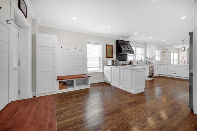 kitchen featuring decorative light fixtures, a peninsula, light countertops, premium range hood, and white cabinetry