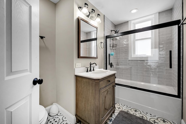 bathroom featuring tile patterned flooring, toilet, bath / shower combo with glass door, vanity, and baseboards