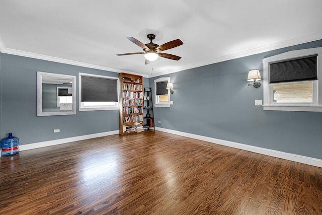 empty room featuring dark wood finished floors, a wealth of natural light, ornamental molding, ceiling fan, and baseboards