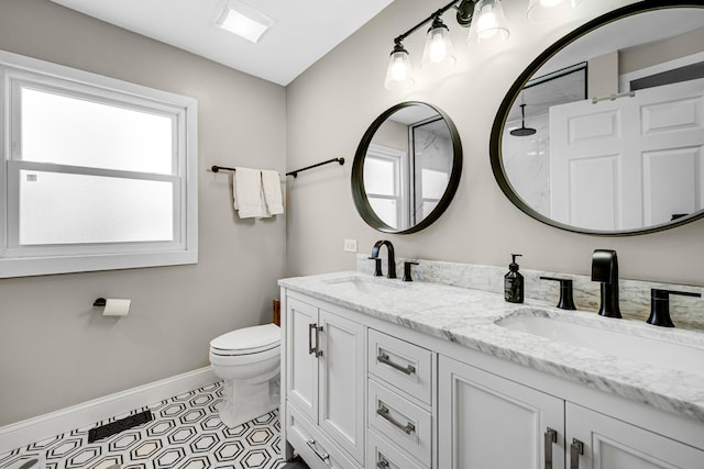 full bath with double vanity, a sink, toilet, and baseboards