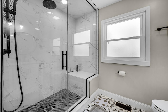 full bathroom featuring a marble finish shower, toilet, and baseboards